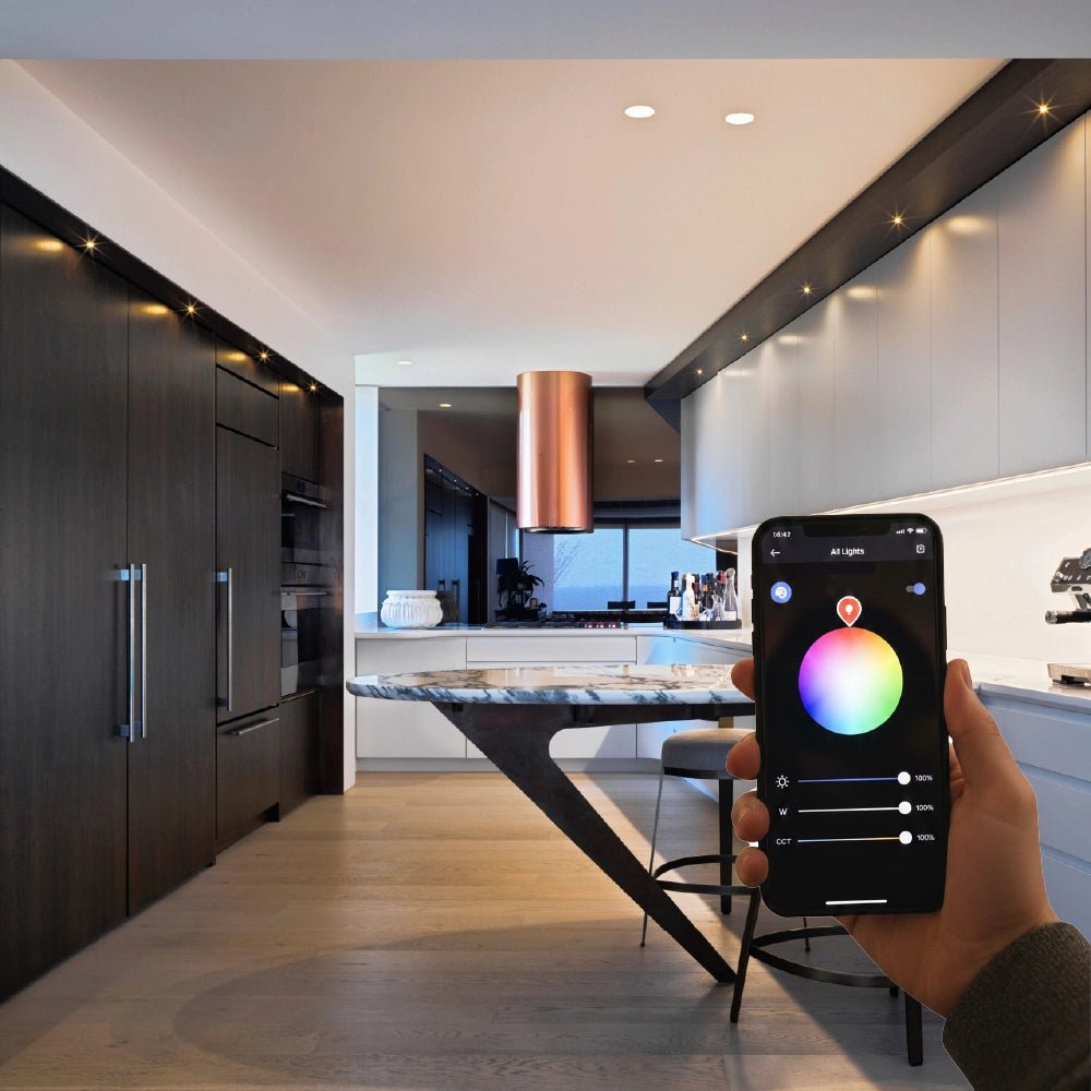 Person using a smartphone app to control lighting in a modern kitchen.