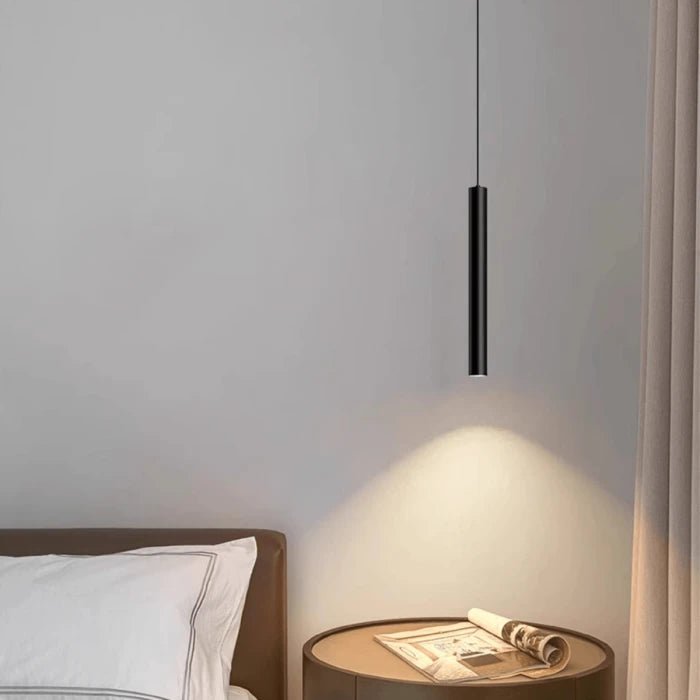 Modern pendant light hanging above a bedside table with a newspaper in a bedroom setting.