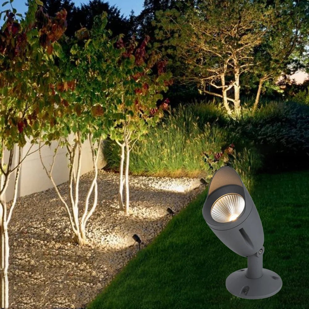 Garden lighting fixture illuminating a pathway with trees and grass in the background