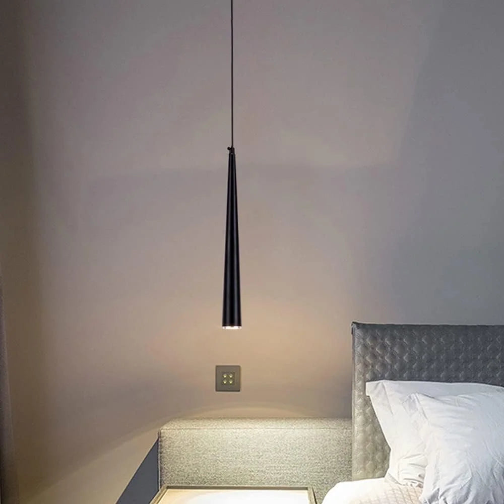 Modern pendant light hanging above a bed in a bedroom setting.