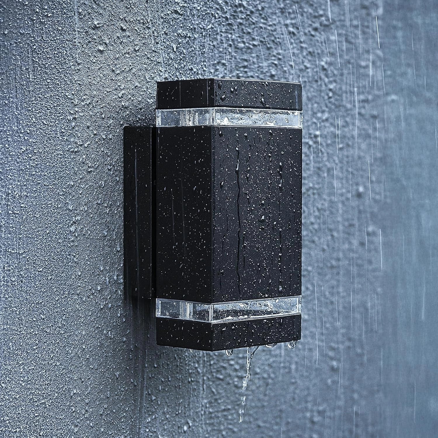 Black outdoor wall light fixture on a textured gray wall with raindrops.