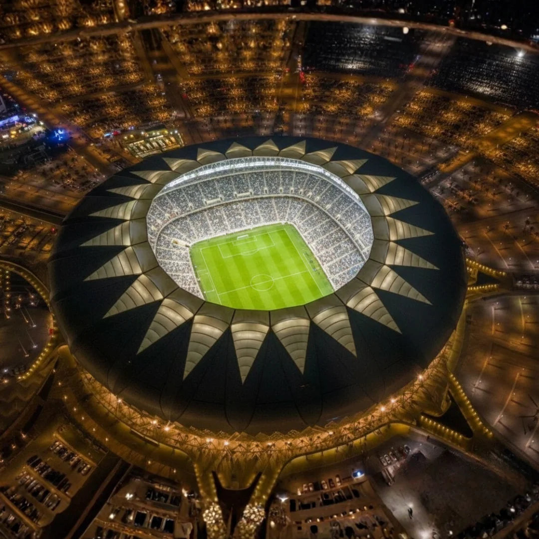 Aerial view of a large stadium with a green field at night.