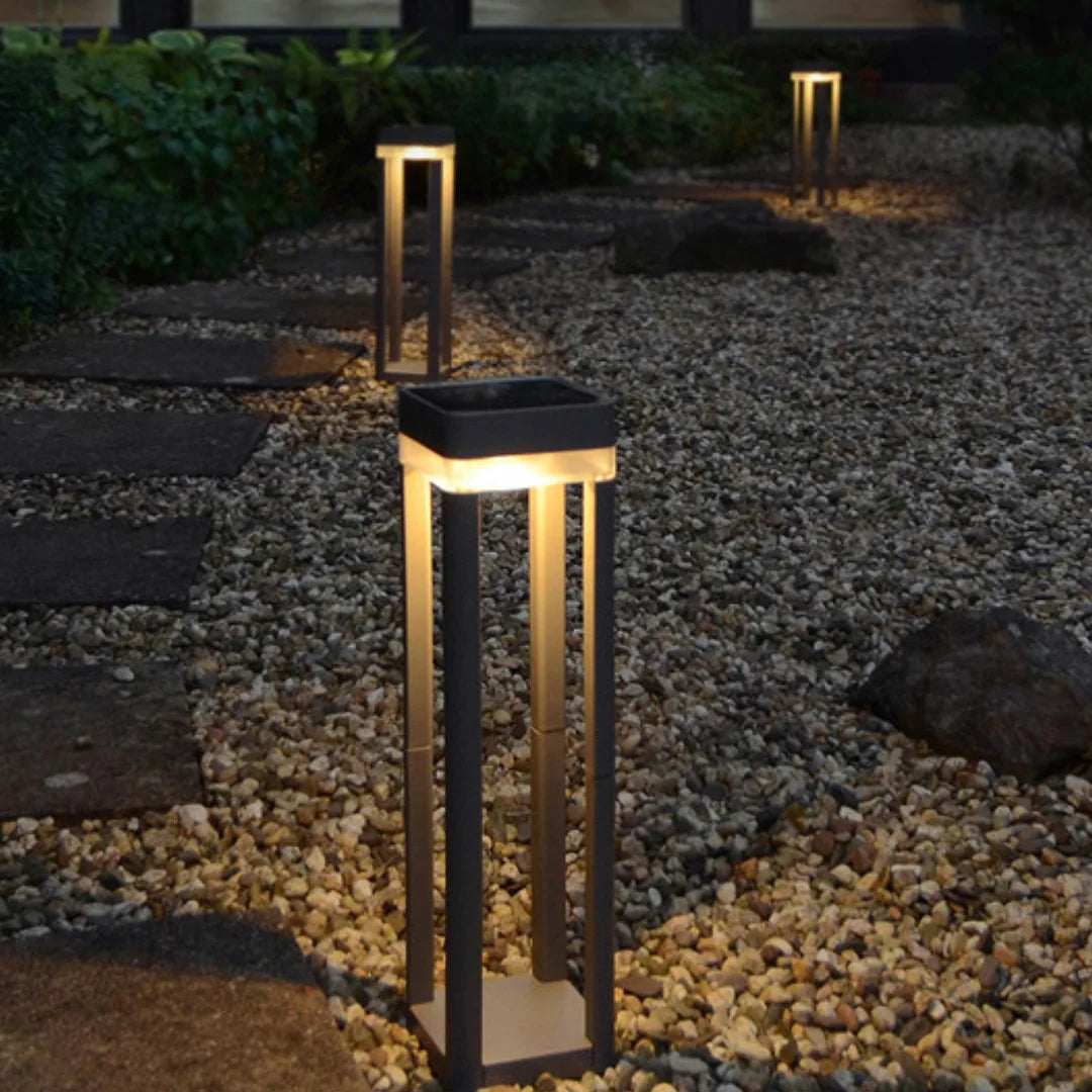 Solar-powered garden lights on a pebbled pathway at night