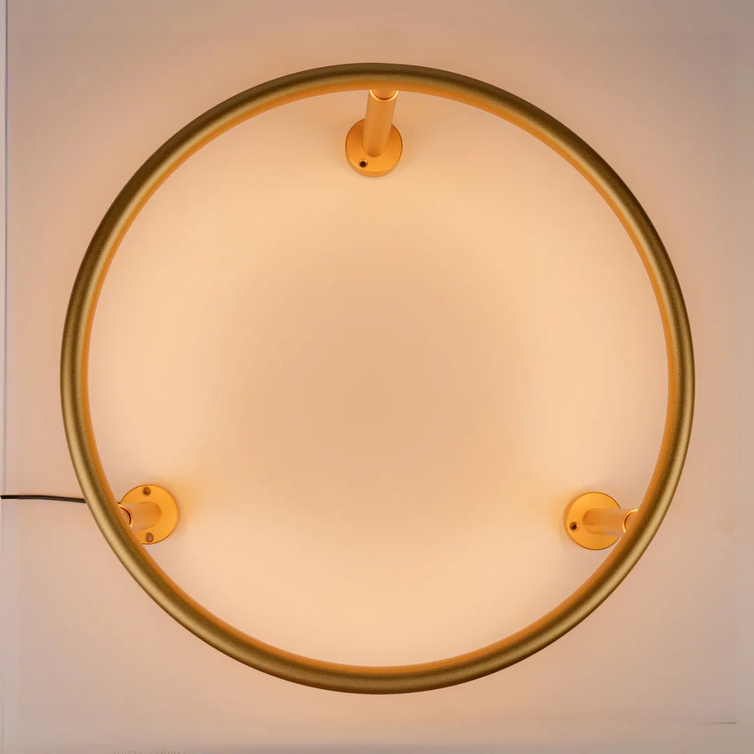 Round wall light fixture with gold frame on a white background
