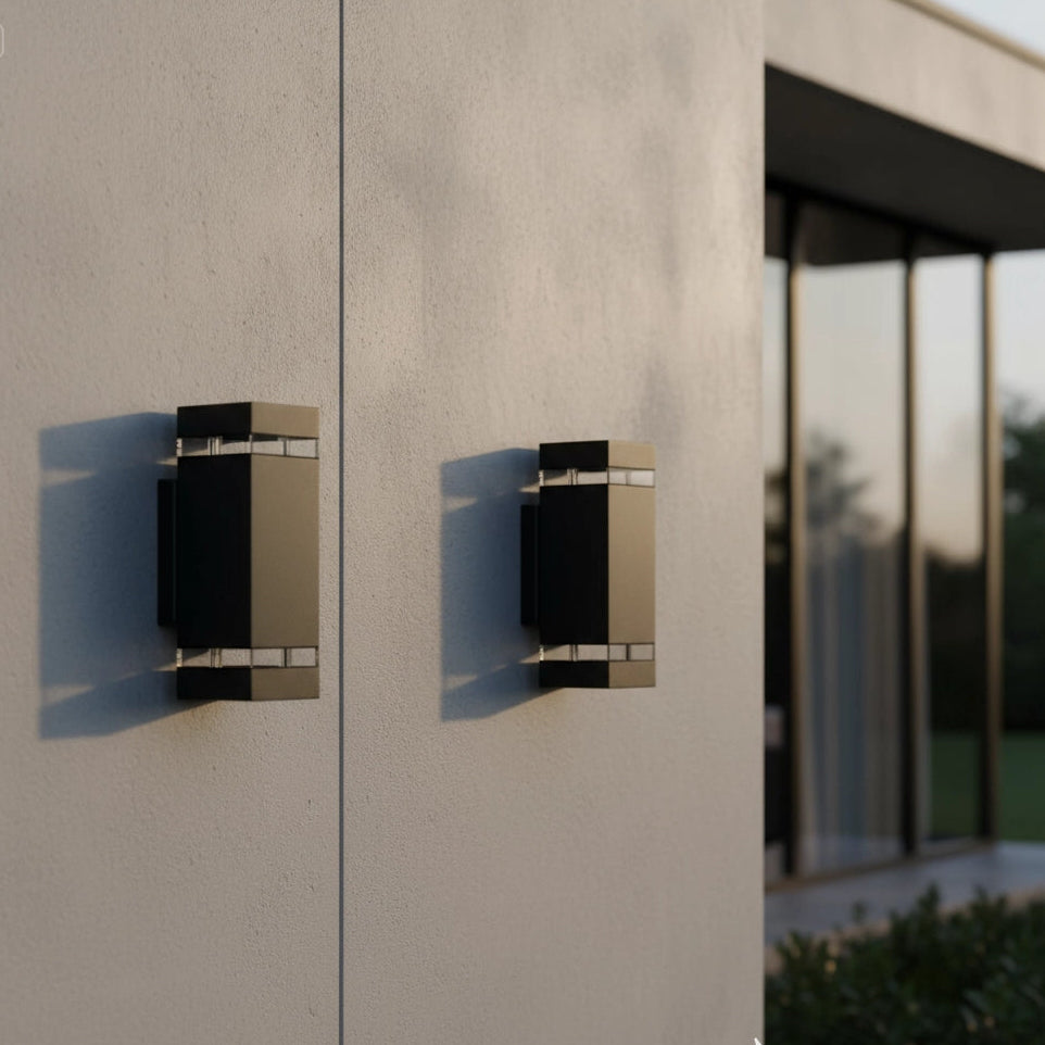 Modern outdoor wall lights on a concrete wall with a blurred window in the background.