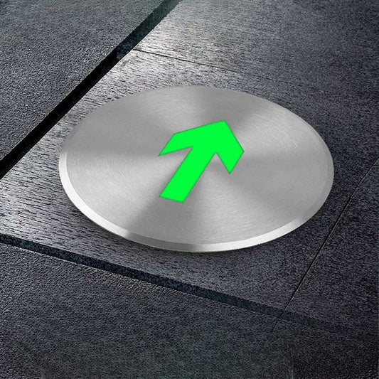 Metallic disc with a green arrow on a gray pavement