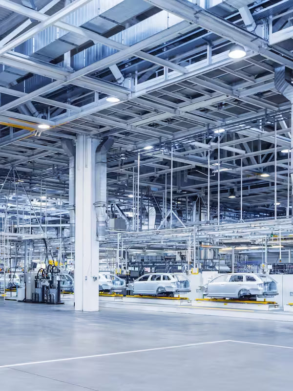 Automotive assembly line in a factory with cars in various stages of production.