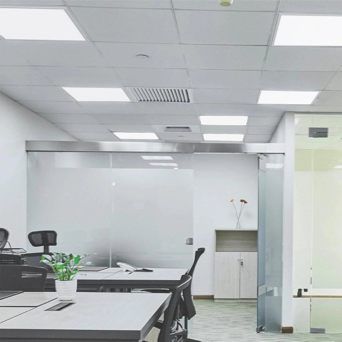 Modern office space with glass walls and white tables.