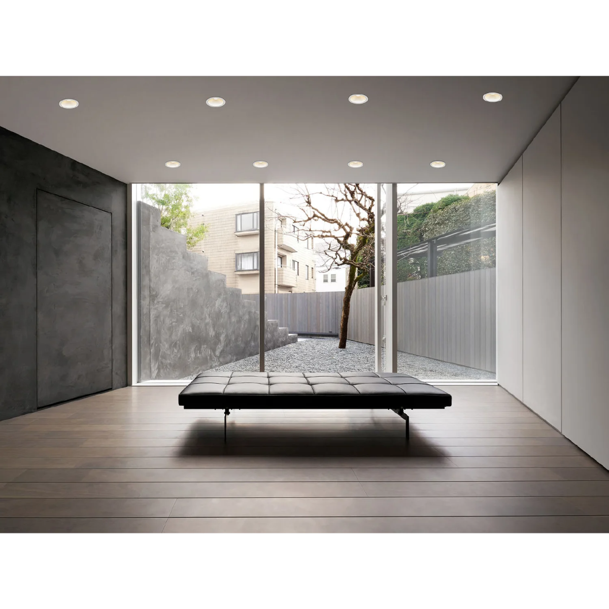 Modern interior with a bench and large glass doors leading to an outdoor area.