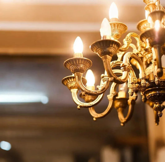 Gold chandelier with lit candles against a blurred background