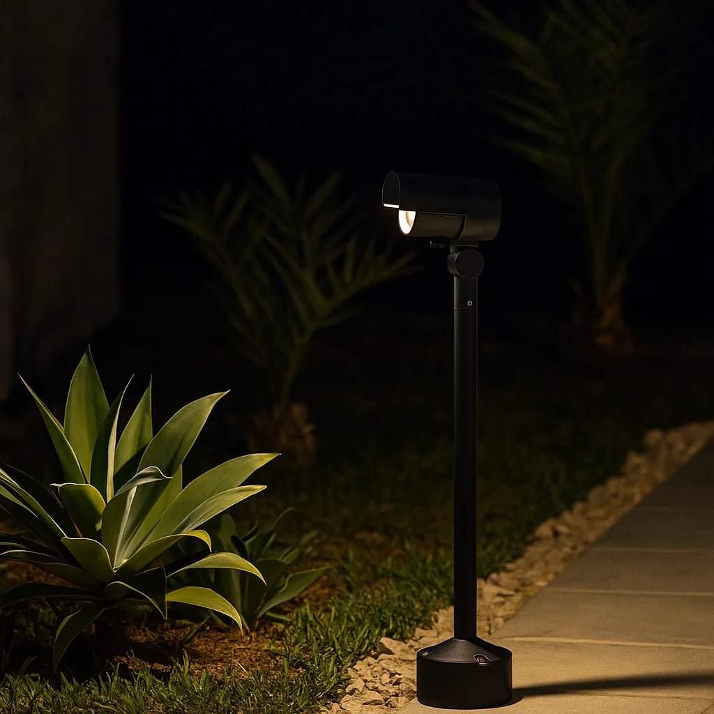 Black outdoor garden light fixture illuminating a pathway at night.