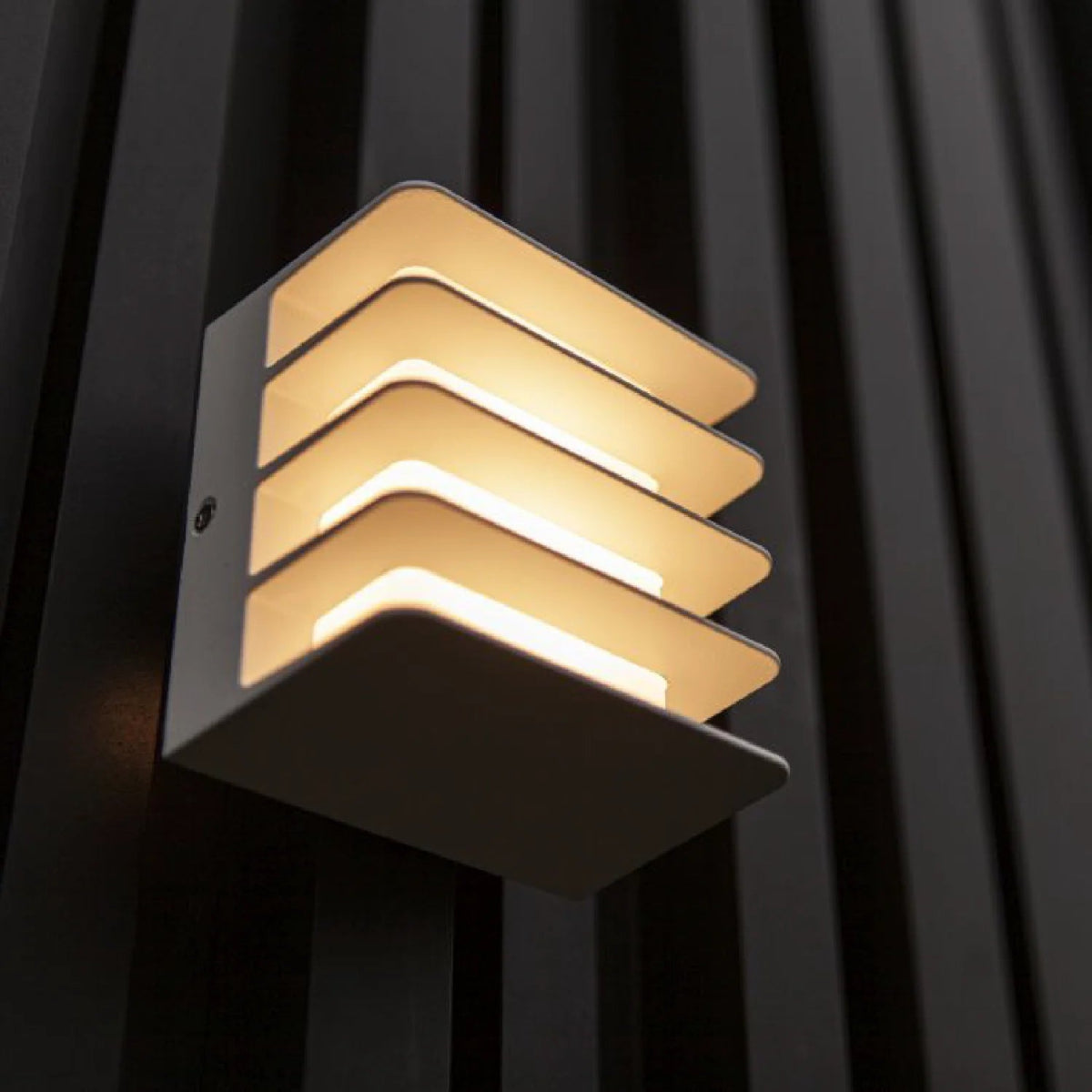 Modern outdoor wall light fixture with geometric design on a dark background