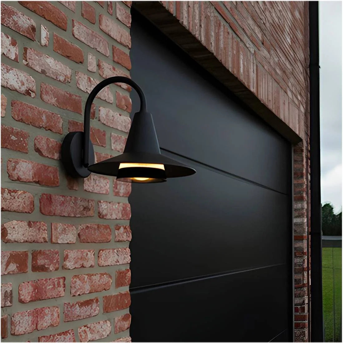 Black outdoor wall light fixture on a brick wall next to a garage door.
