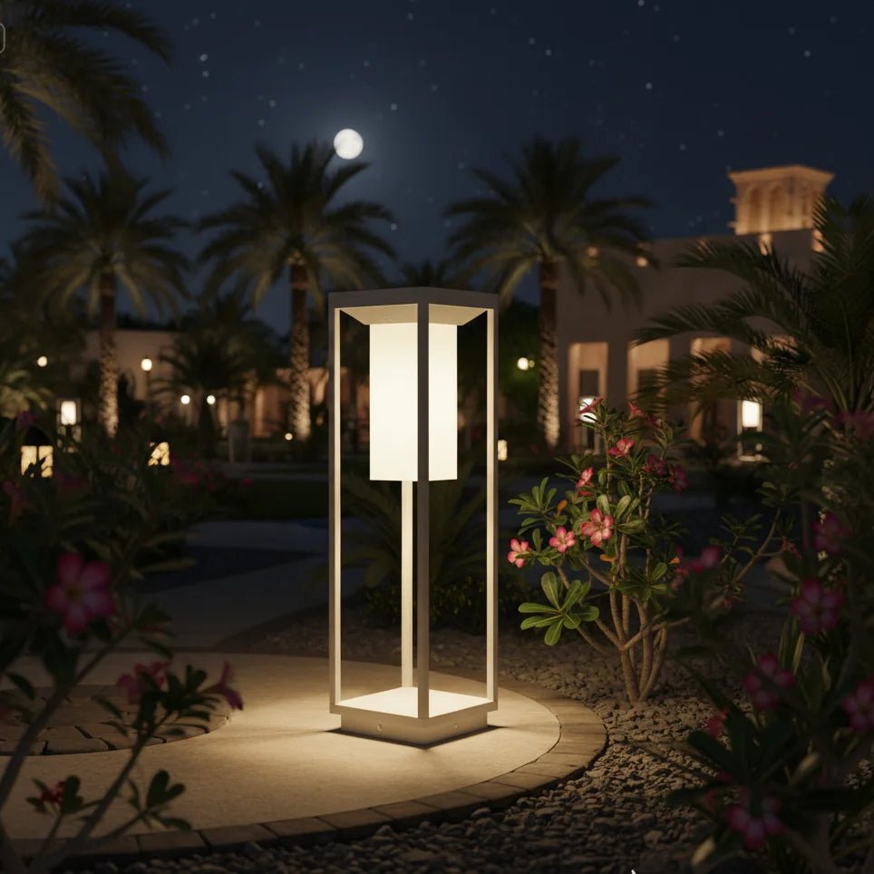 Decorative outdoor lamp in a garden setting with palm trees and a building in the background.