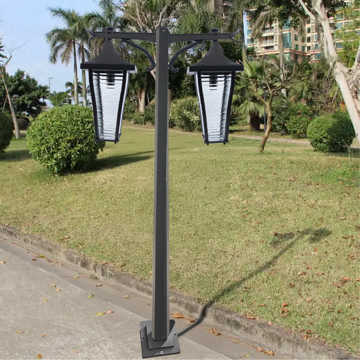 Black outdoor lamp post with two lantern-style lights on a grassy area.
