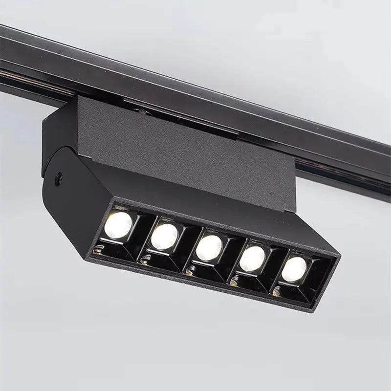 Black track light fixture with five white LED lights on a gray background