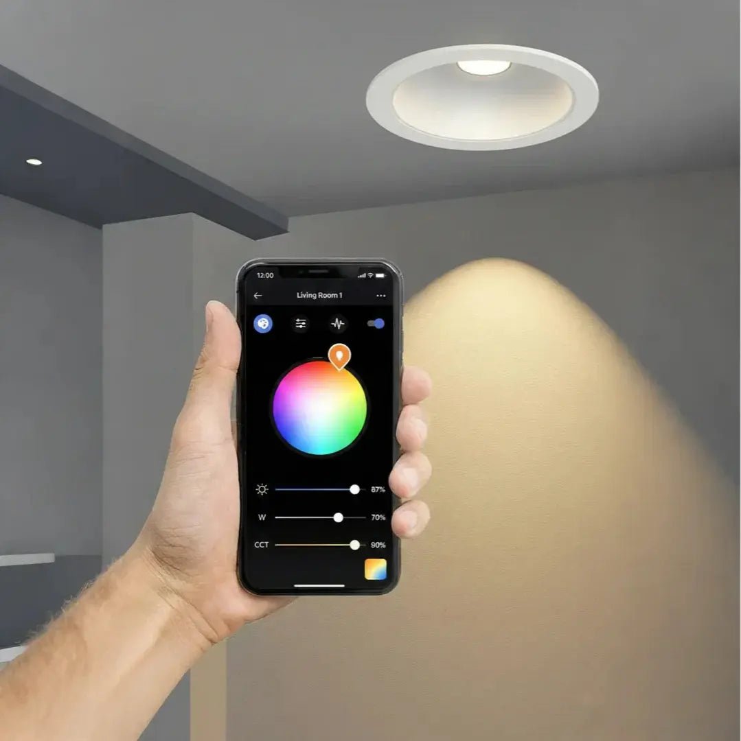 Hand holding a smartphone with a lighting control app, showing a smart light fixture in a room.