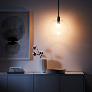 Modern interior with a pendant light, vase, and abstract art on a wall.