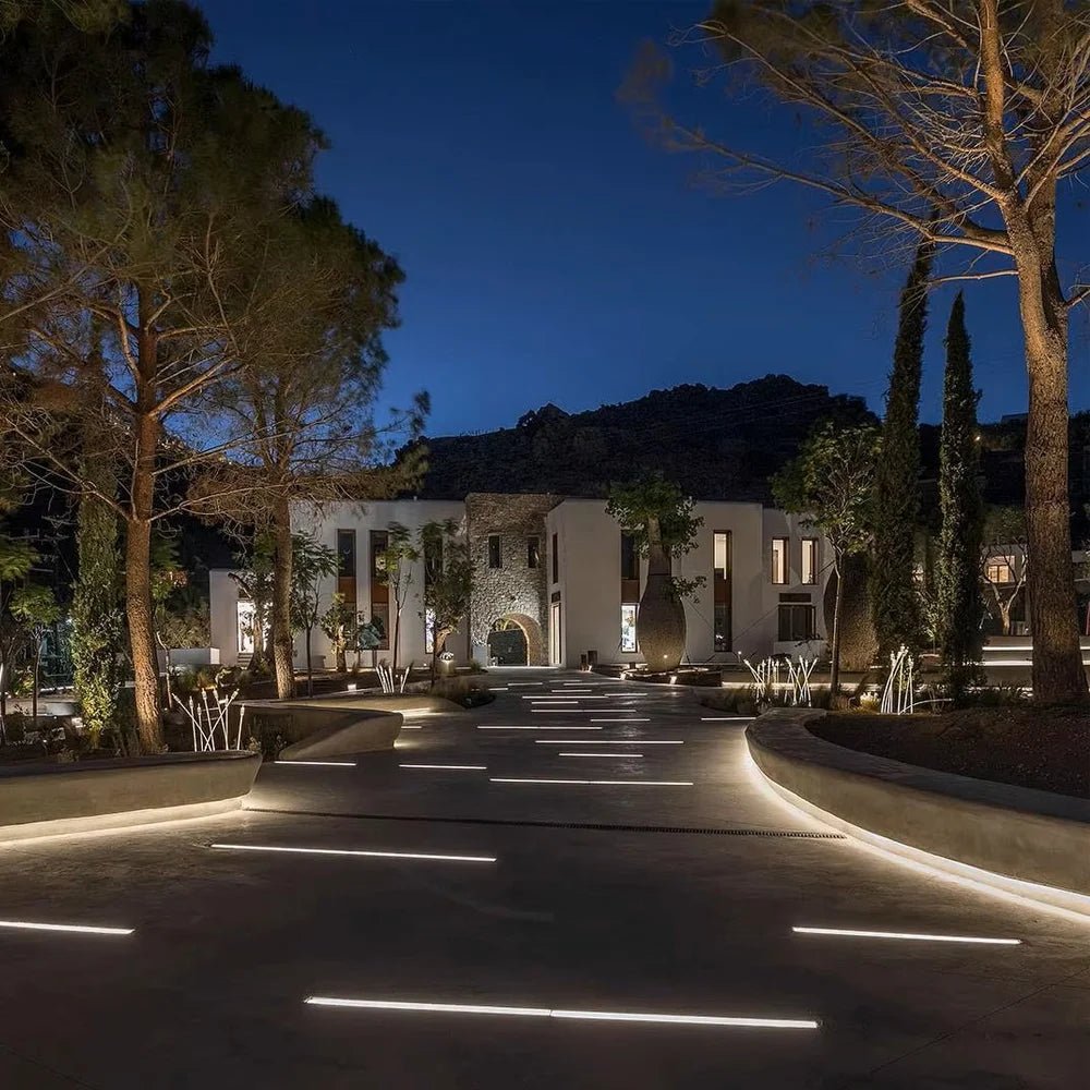 Evening view of a modern building with illuminated pathways and trees.