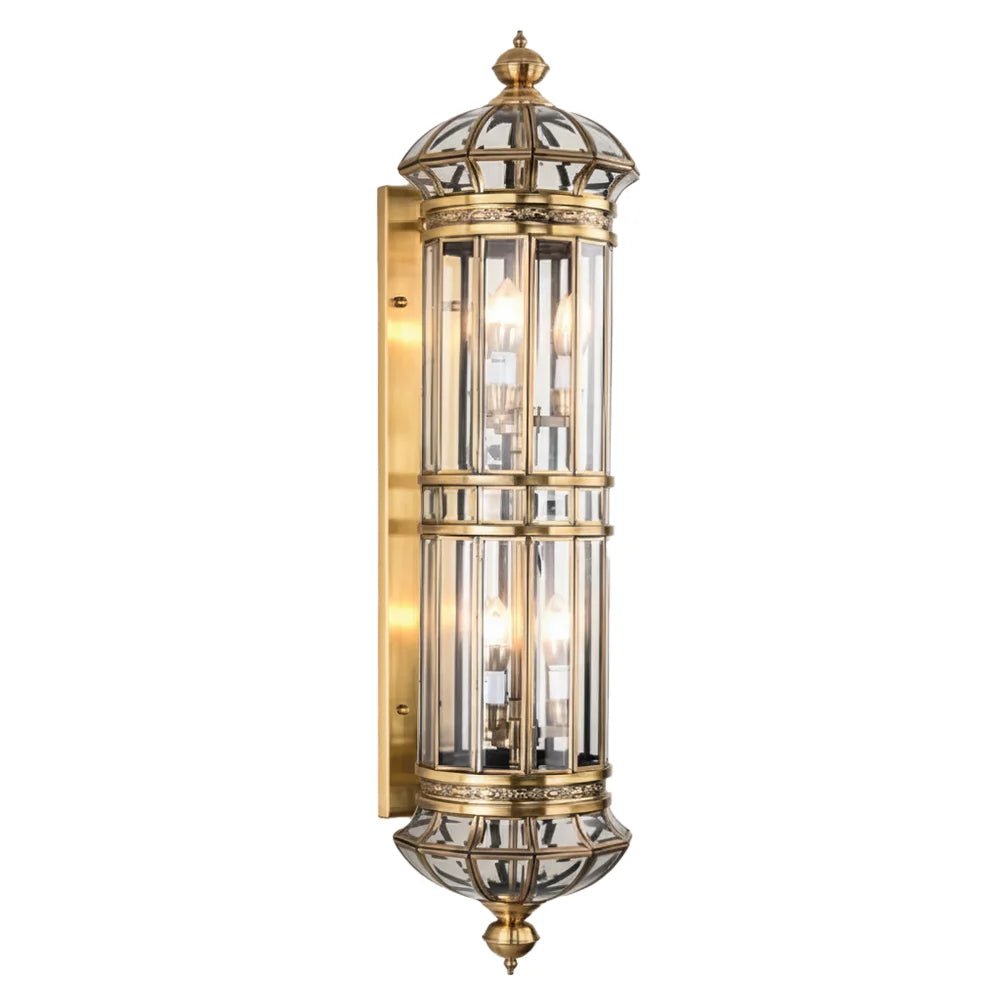 Decorative outdoor wall light fixture with gold finish and glass panels on a white background