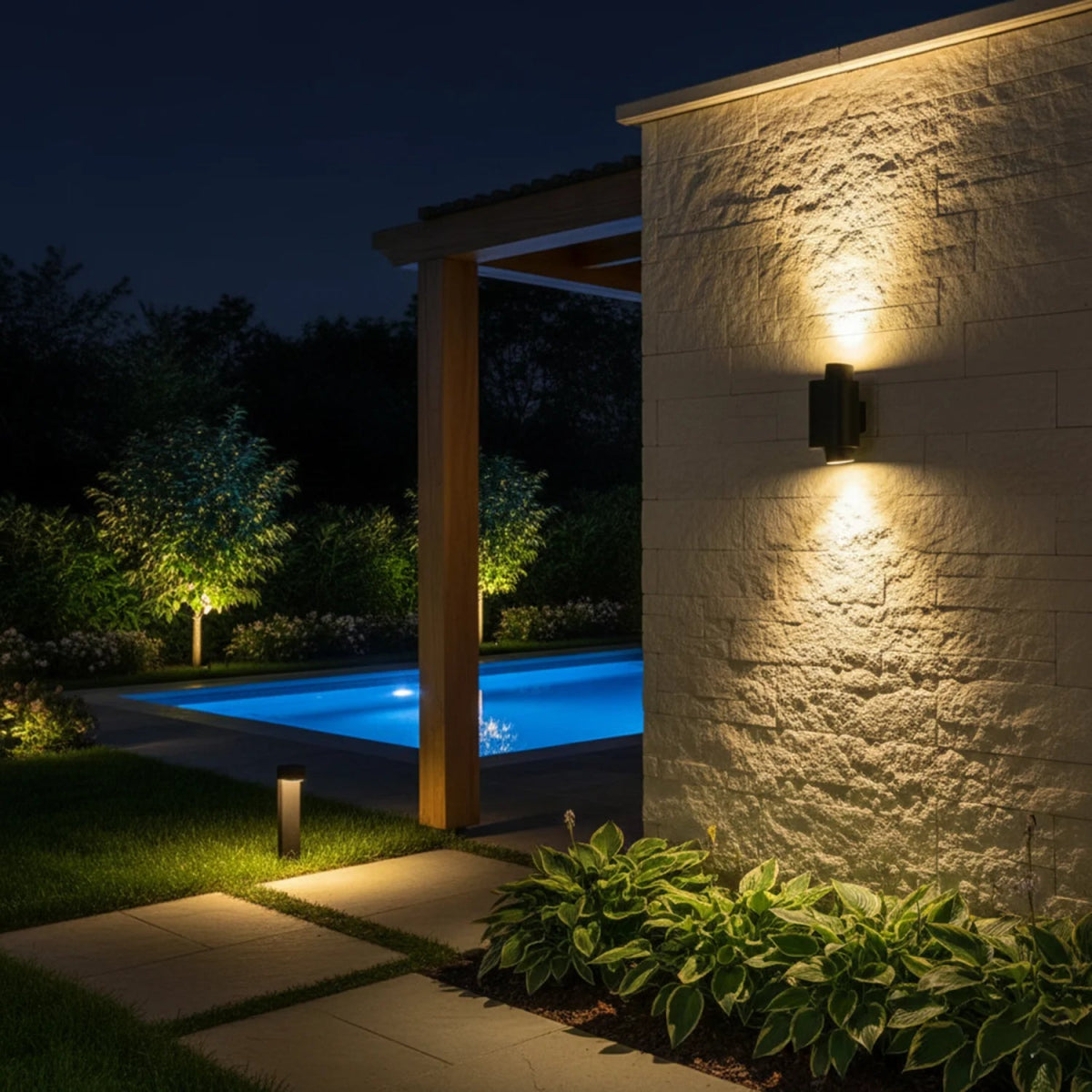 Outdoor setting with a pool, pathway, and wall-mounted light fixture at night.