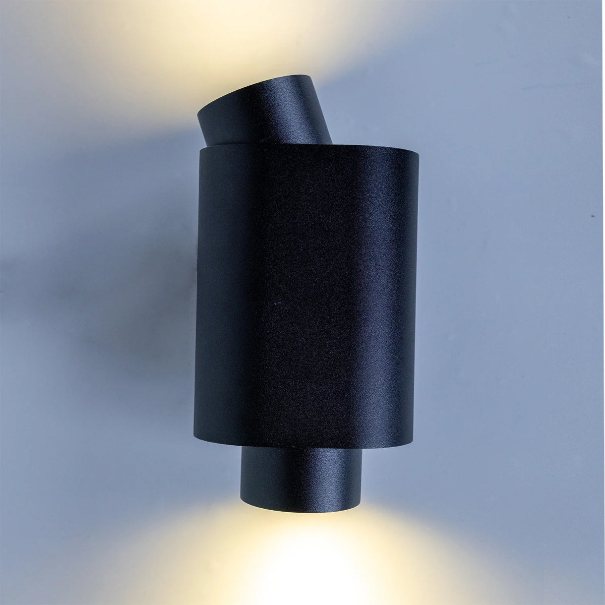 Black cylindrical wall light fixture on a gray background