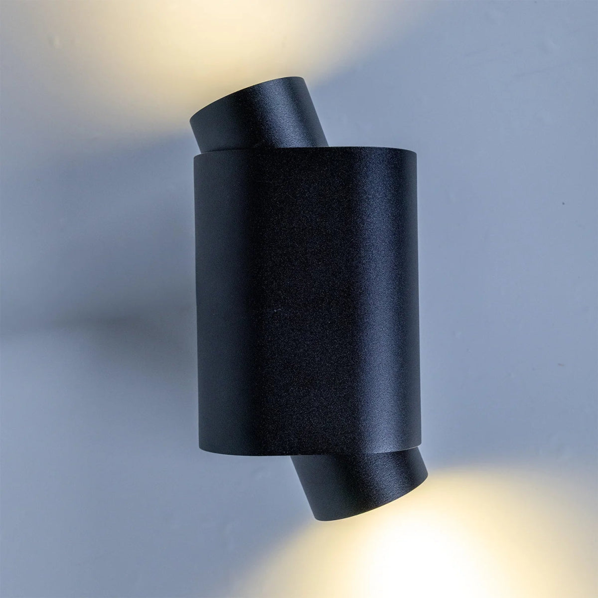 Black cylindrical wall light fixture on a gray background