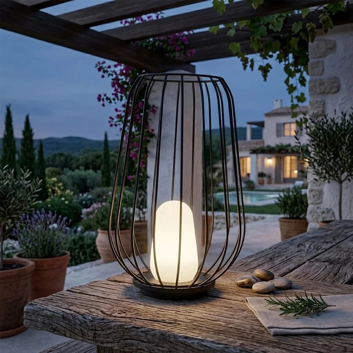 Decorative outdoor lamp on a table with a garden and pool in the background