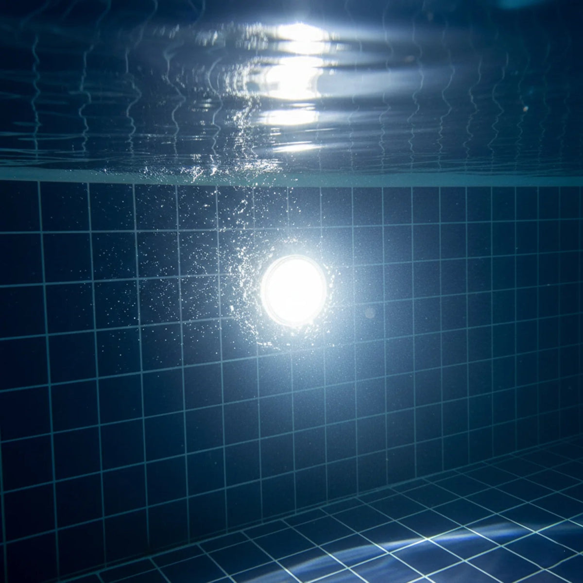 Underwater view of a pool with tiled bottom and light source
