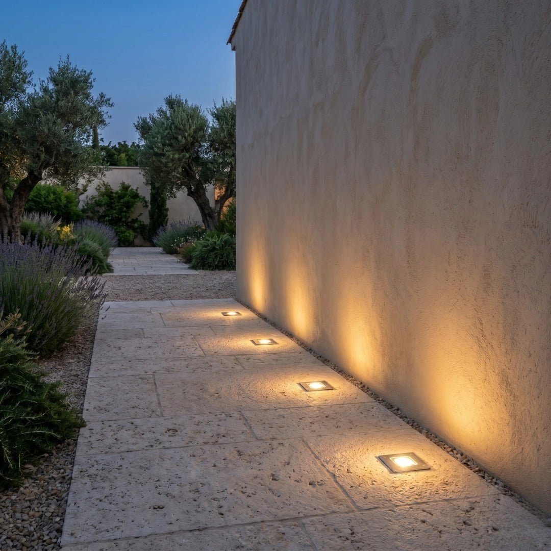 Pathway with embedded lights along a textured wall in a garden setting
