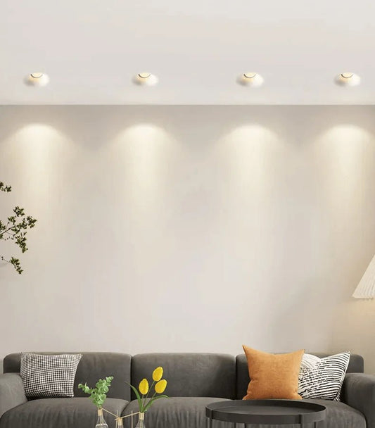 Modern living room with gray sofa, decorative pillows, and wall lights.