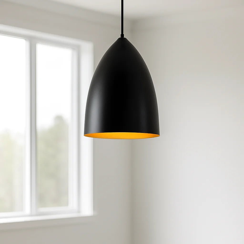 Black pendant light with a gold interior hanging in a room with a window.