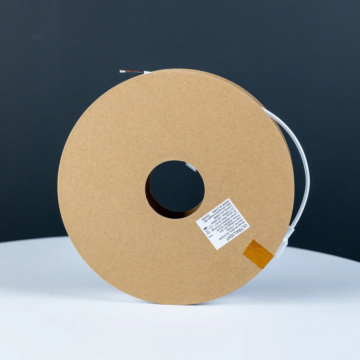 Spool of brown paper with a label on a white surface and dark background