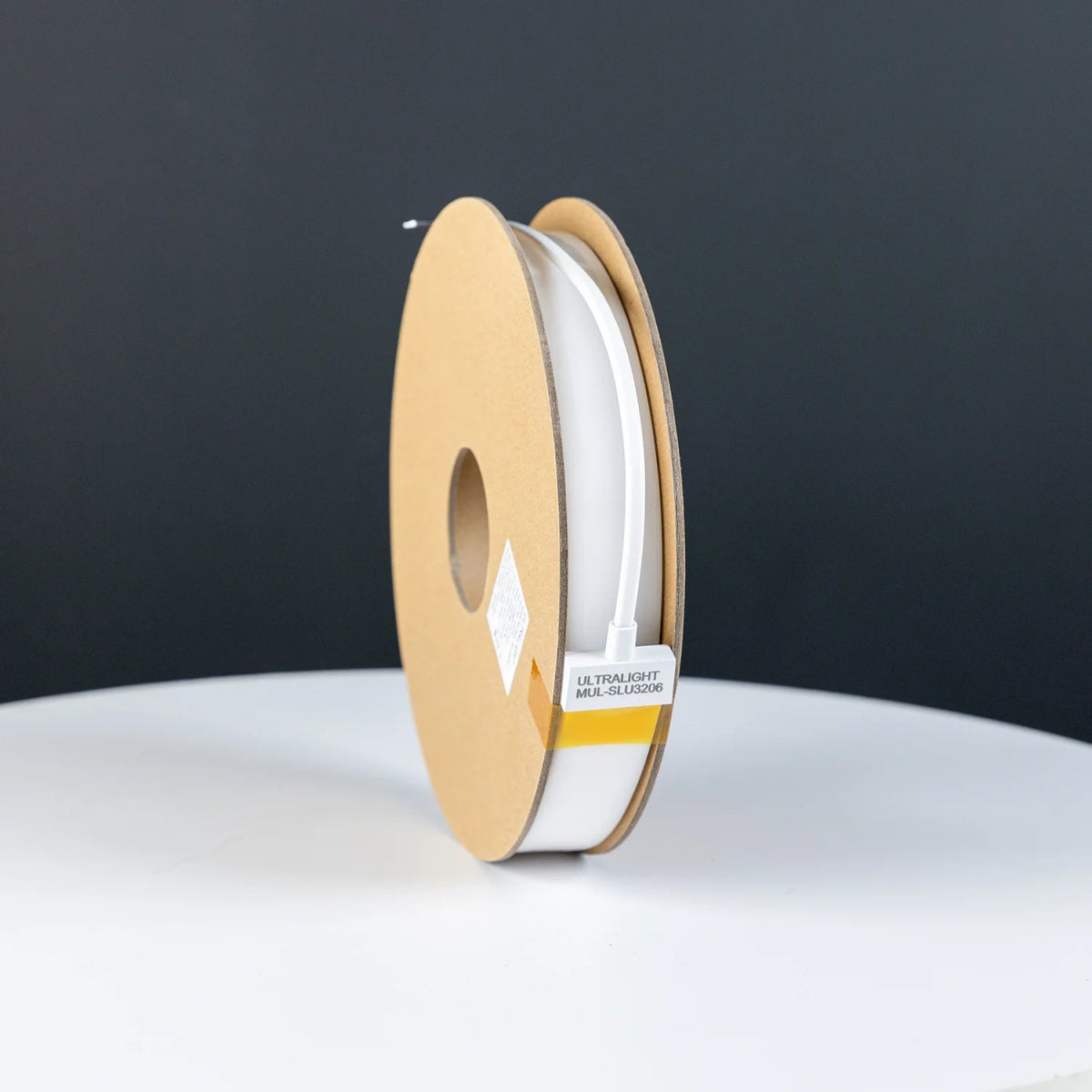 Spool of white thread on a wooden reel with a dark background