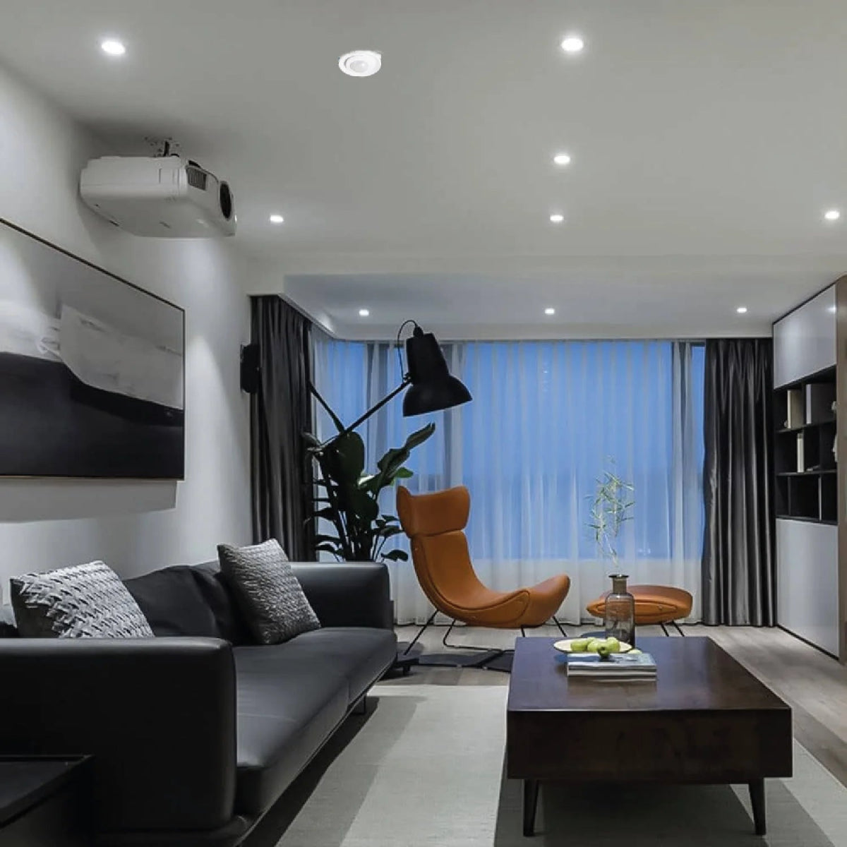 Modern living room with a gray sofa, orange chair, and a TV mounted on the wall.