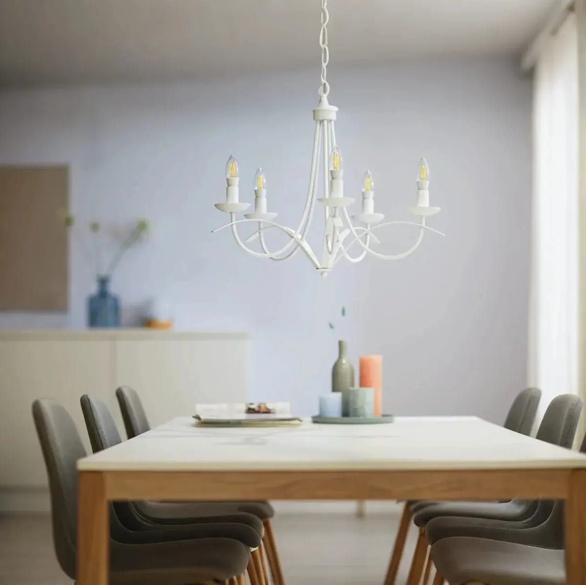 Dining room with a white chandelier, table, and chairs.