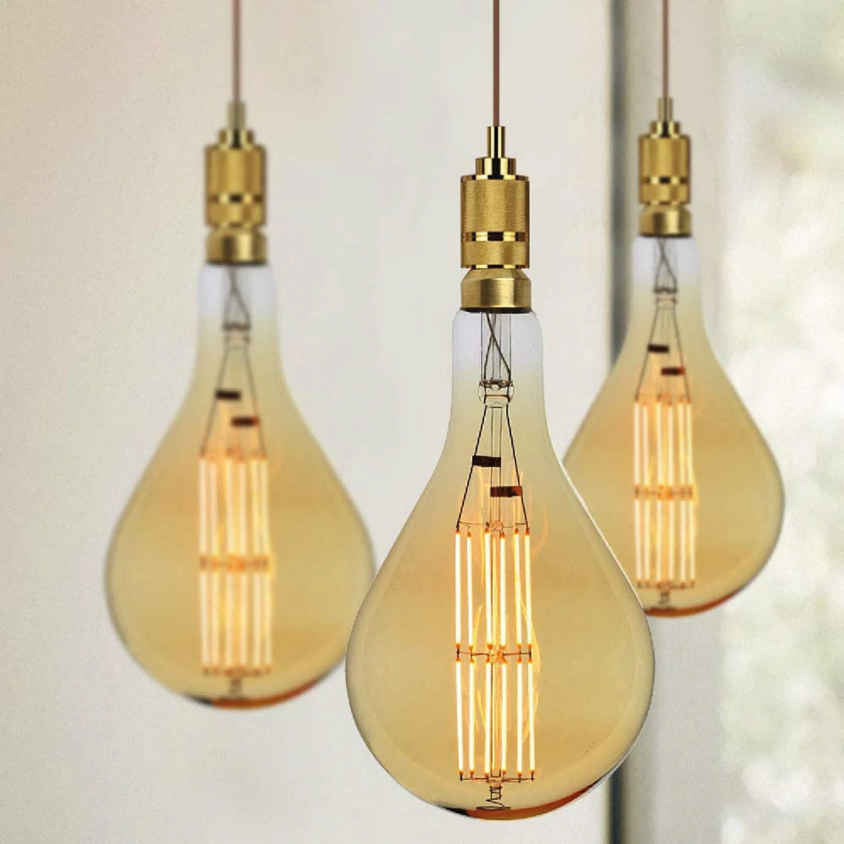 Three vintage-style light bulbs hanging against a blurred background