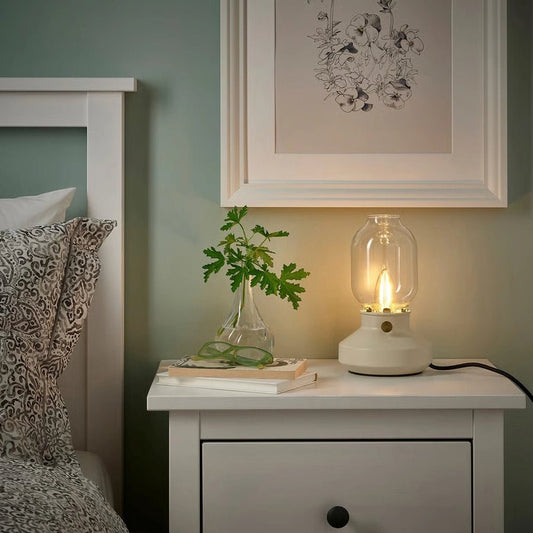 Lamp on a nightstand next to a bed with decorative elements.