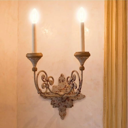 Decorative wall sconce with two candles on a beige wall.