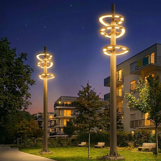 Decorative street lights in a park with buildings in the background at night.