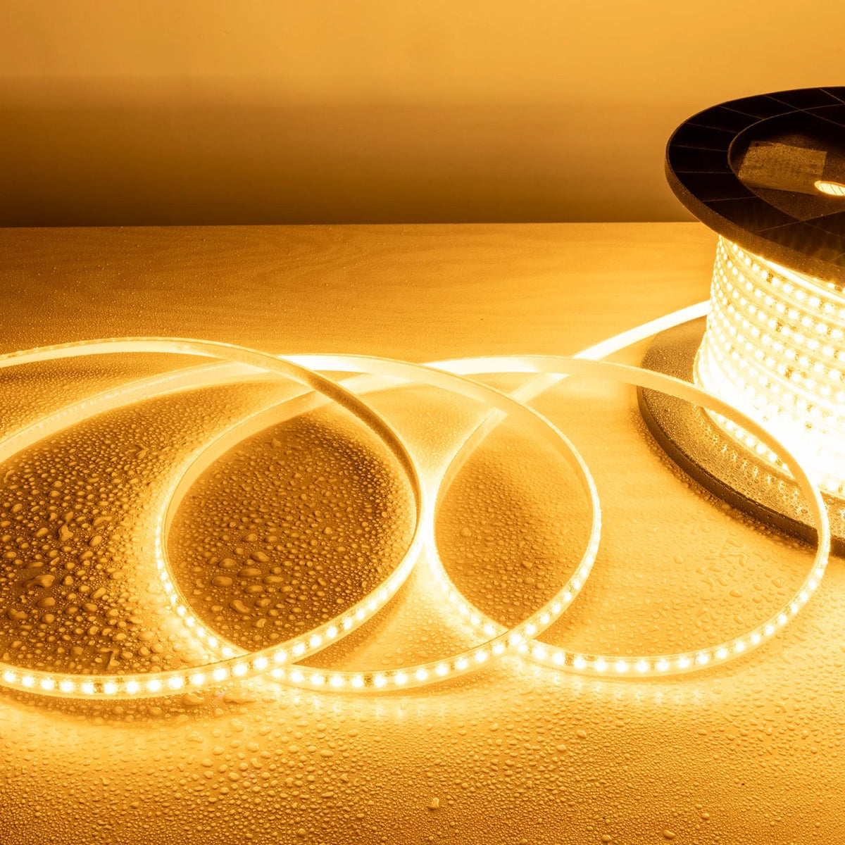 Spool of LED strip light on a reflective surface with a warm glow.