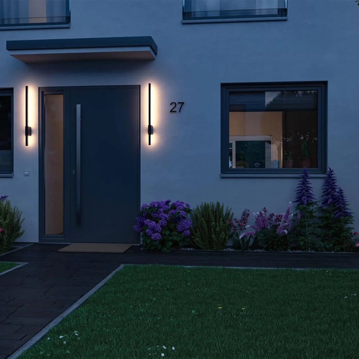 Modern house exterior with illuminated wall lights and address number 27 at night.