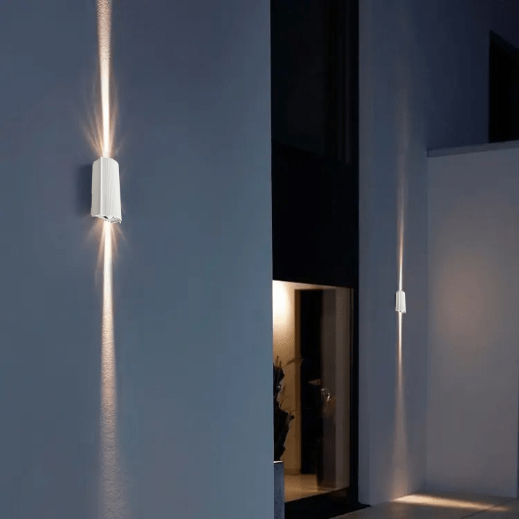 Modern wall lights on a dark wall with a softly lit room in the background