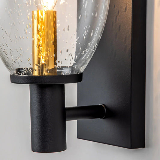 Wall-mounted light fixture with black base and gold interior on a gray background