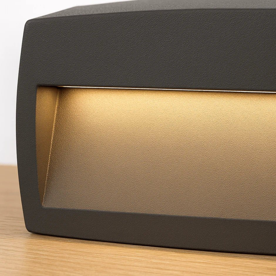 Modern outdoor wall light fixture on a wooden surface with a neutral background