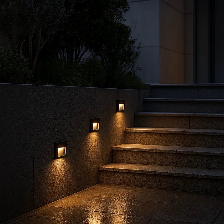 Stairway illuminated by wall-mounted lights in a dark outdoor setting