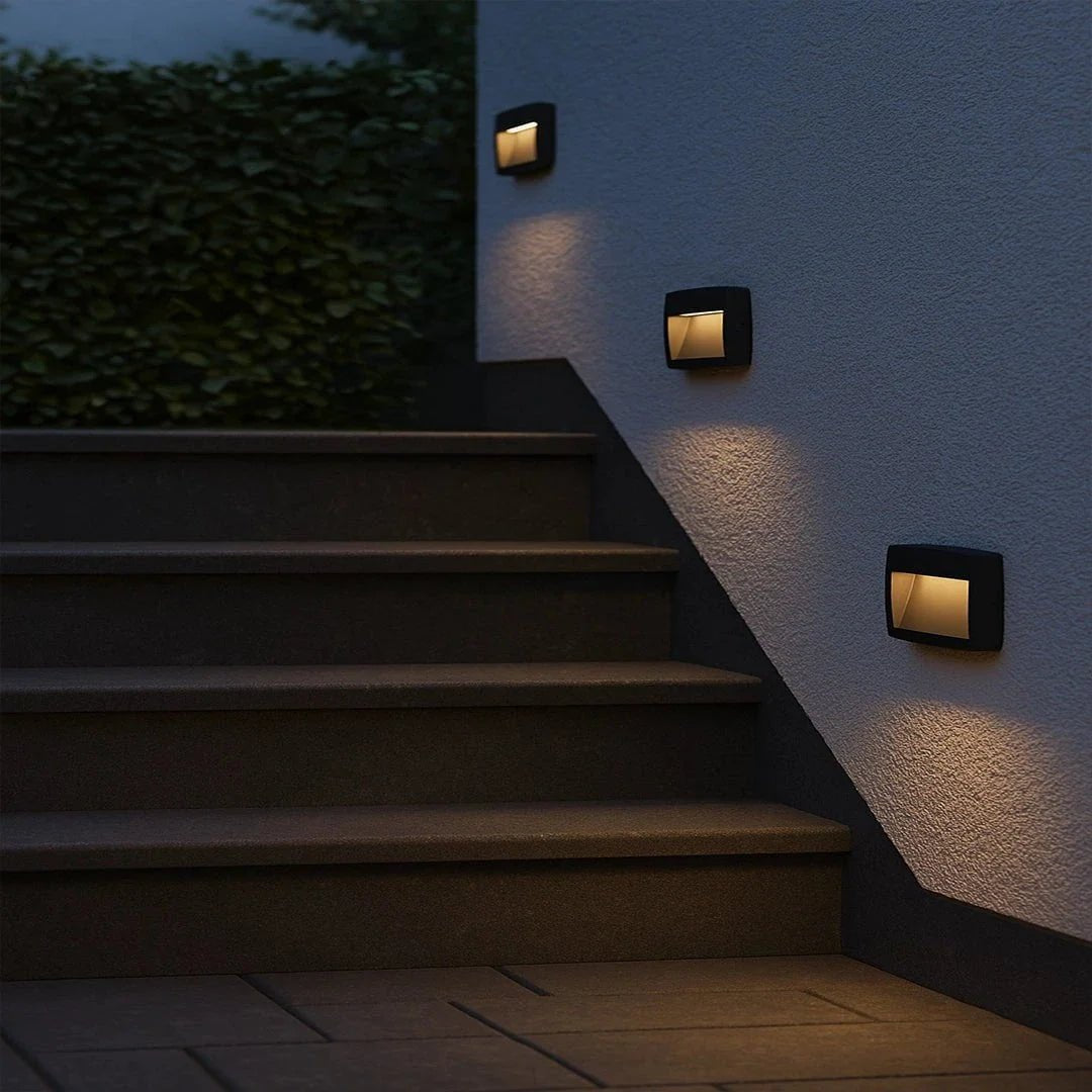 Staircase with wall-mounted outdoor lights illuminating the steps at night.