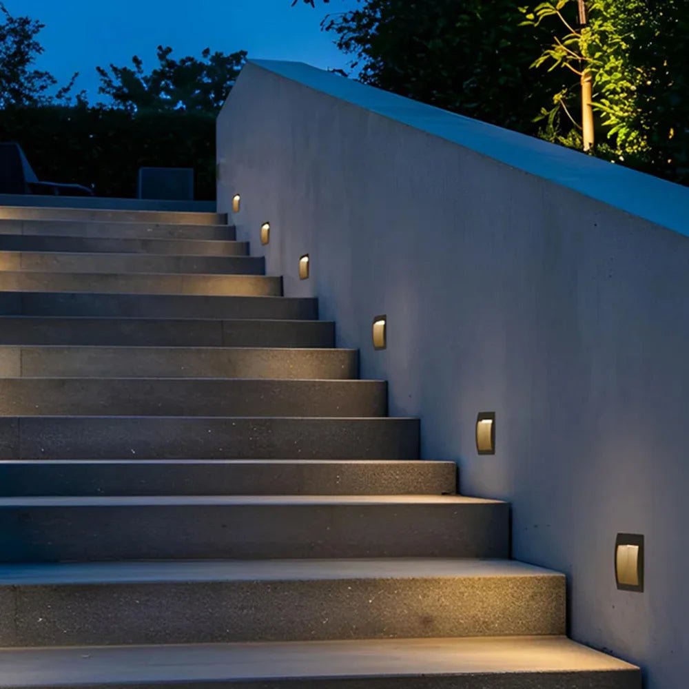 Staircase with wall-mounted lights on a building exterior at night.