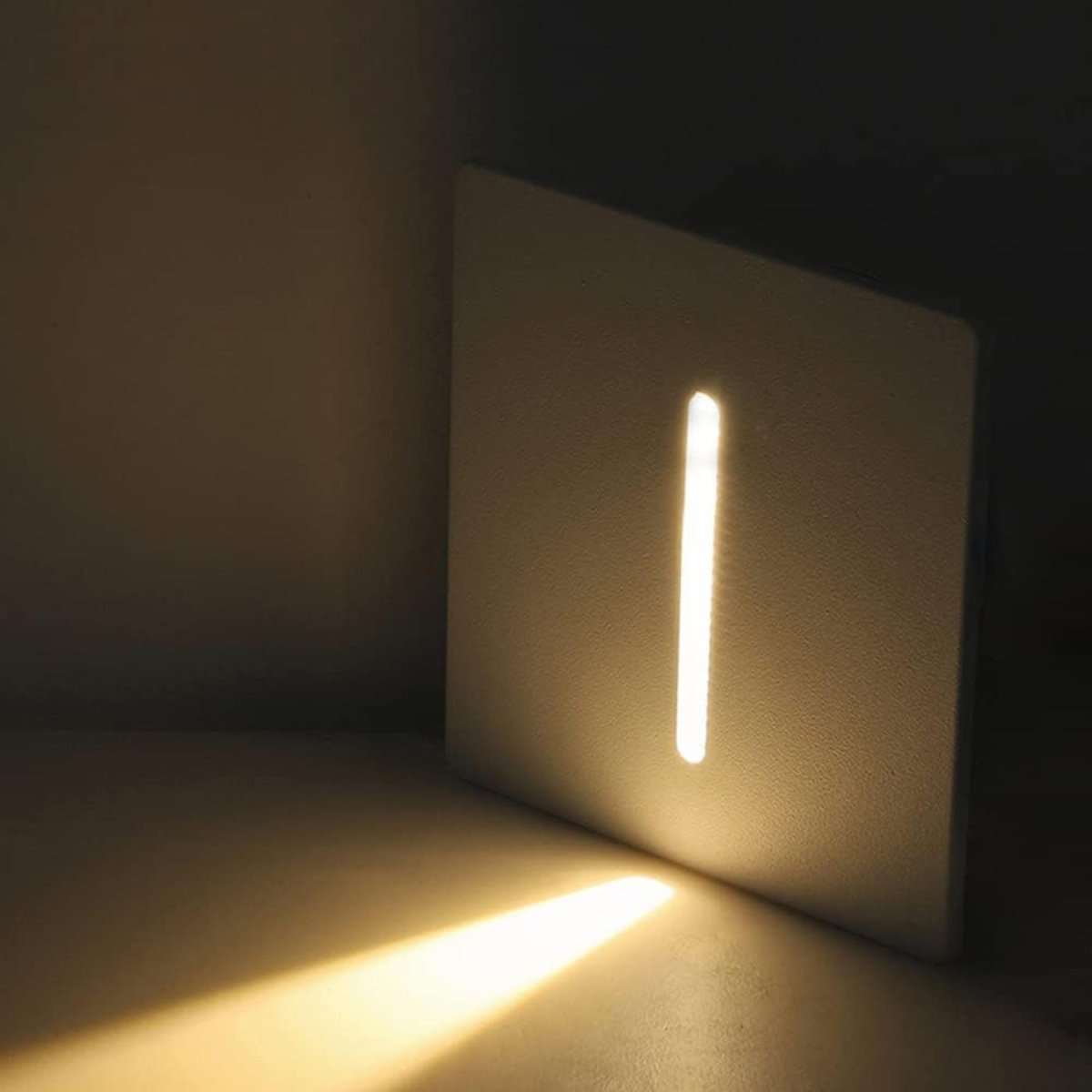 Square wall light emitting a warm glow on a dark background