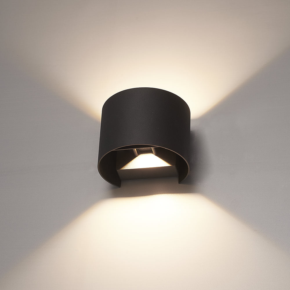 Black cylindrical wall light fixture on a gray wall